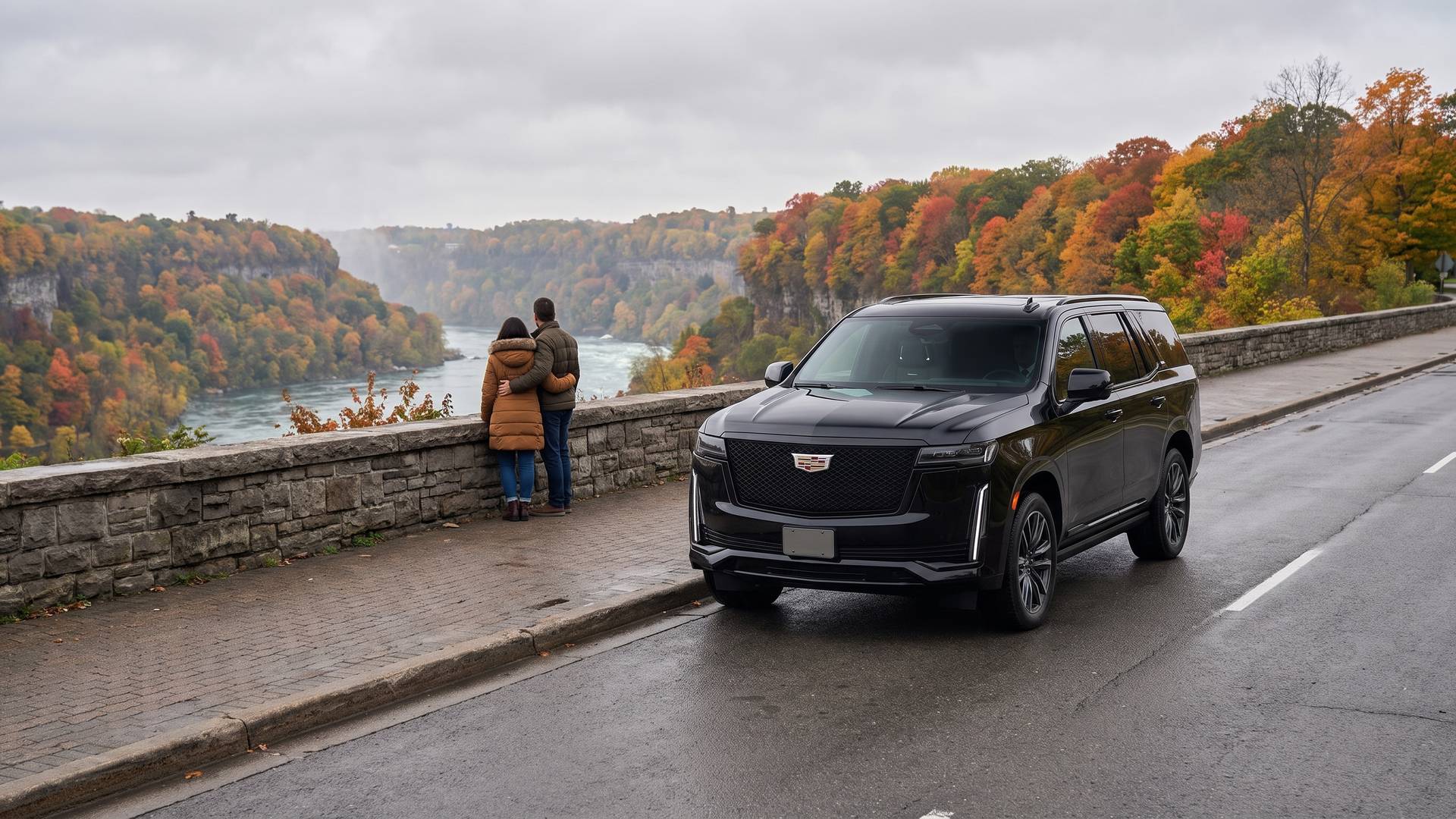 A couple at a stone wall looking out over the Niagara River gorge in autumn, with a black Cadillac Escalade waiting behind them